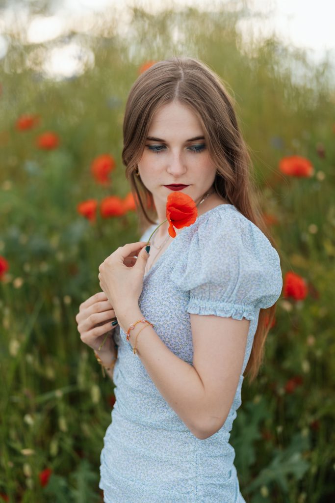 Lektorin mit blauem Kleid und roter Mohnblume in der Hand - Lektorat Belletristik